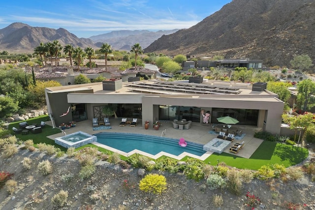 back of house with a pool with hot tub, a mountain view, and a patio area