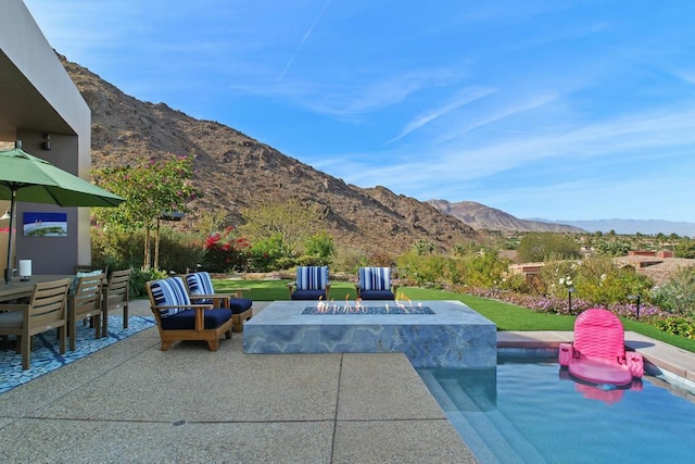 view of patio with a mountain view and an outdoor fire pit