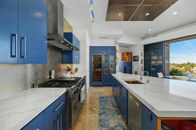 kitchen with blue cabinetry, appliances with stainless steel finishes, light stone countertops, and extractor fan