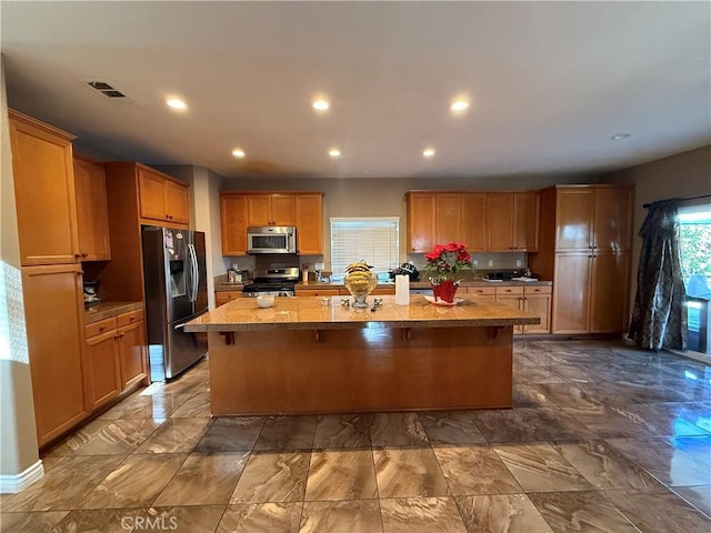 kitchen with stainless steel appliances, a breakfast bar area, and a center island with sink