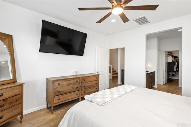 bedroom with ceiling fan, ensuite bath, and hardwood / wood-style floors