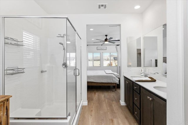 bathroom with a shower with door, wood-type flooring, vanity, and ceiling fan