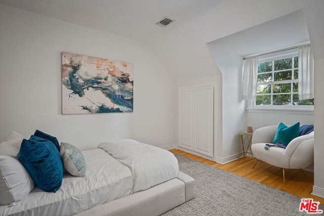 bedroom featuring lofted ceiling and light hardwood / wood-style floors