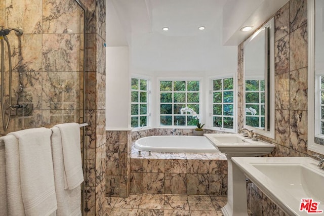 bathroom with plus walk in shower, tile walls, and dual sinks