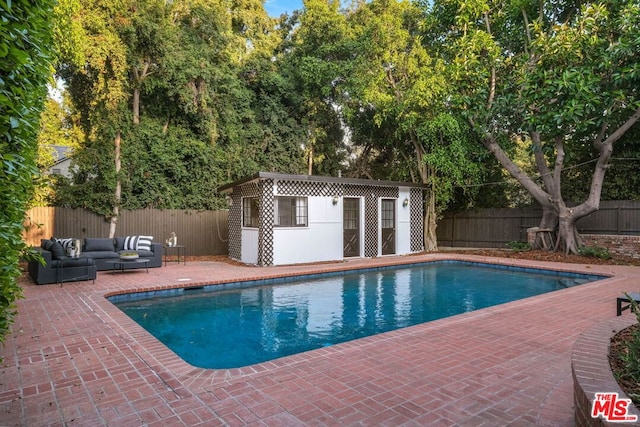 view of pool with an outdoor living space, a patio, and an outdoor structure