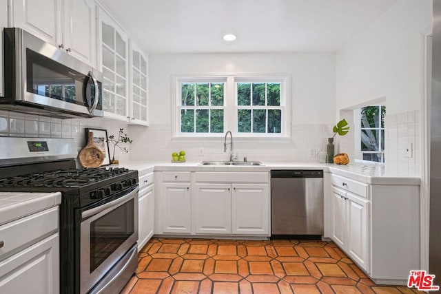 kitchen with sink, tile countertops, stainless steel appliances, and white cabinets