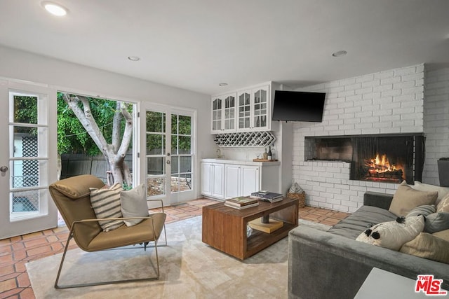 living room with a brick fireplace, light tile patterned floors, and bar area