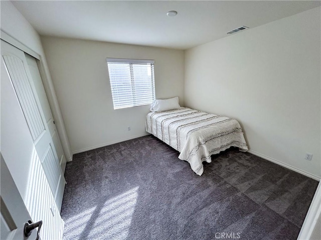 unfurnished bedroom featuring dark colored carpet and a closet