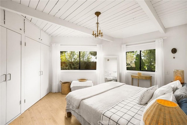 bedroom featuring multiple windows, a notable chandelier, light hardwood / wood-style floors, and beamed ceiling