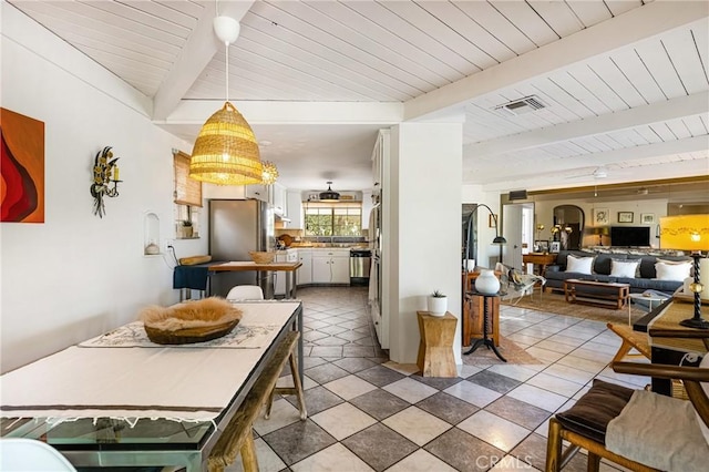 interior space featuring pendant lighting, stainless steel refrigerator, white cabinetry, wood ceiling, and beam ceiling