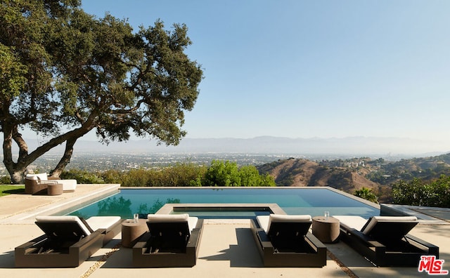 view of pool with a mountain view, a patio area, and an outdoor hangout area