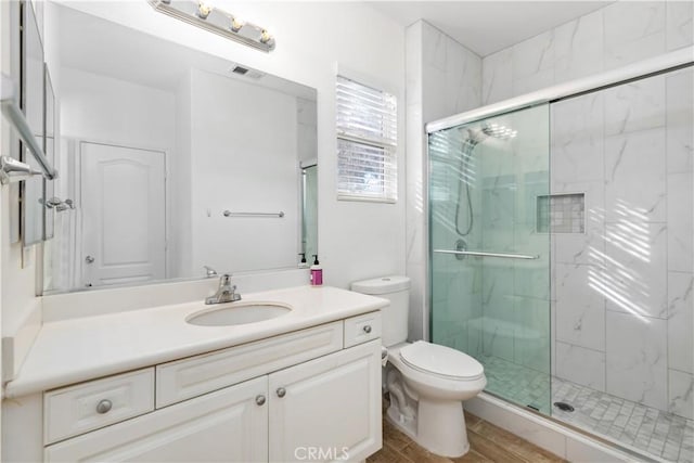 bathroom with hardwood / wood-style flooring, vanity, toilet, and a shower with shower door