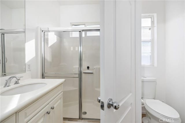 bathroom featuring toilet, vanity, and walk in shower