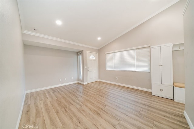 spare room featuring vaulted ceiling, ornamental molding, and light hardwood / wood-style flooring