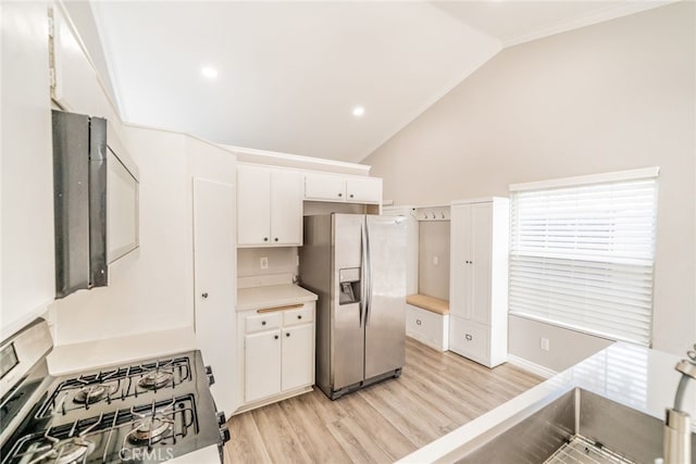 kitchen featuring lofted ceiling, appliances with stainless steel finishes, white cabinets, and light hardwood / wood-style floors