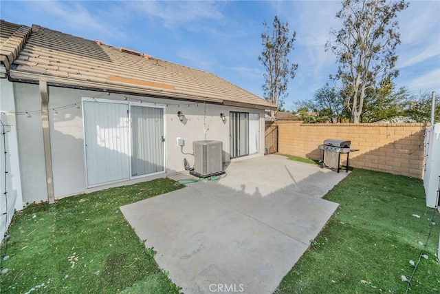 back of house featuring cooling unit, a patio area, and a lawn