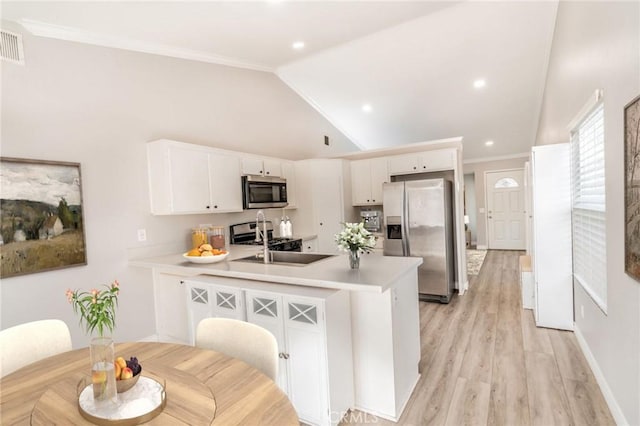 kitchen featuring sink, light wood-type flooring, appliances with stainless steel finishes, kitchen peninsula, and white cabinets