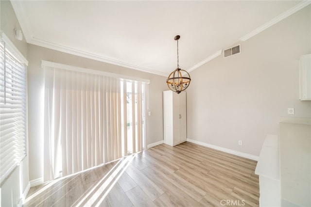 spare room featuring ornamental molding, light hardwood / wood-style floors, and a notable chandelier