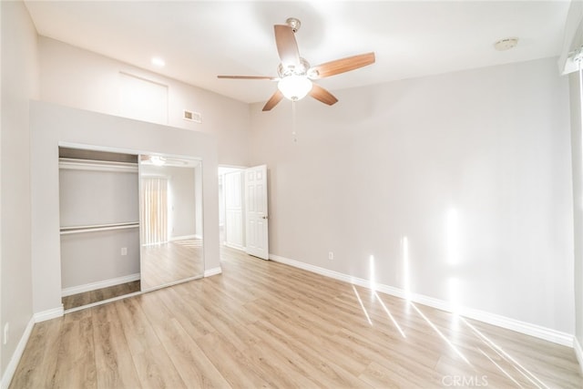 unfurnished bedroom with a towering ceiling, light hardwood / wood-style flooring, ceiling fan, and a closet