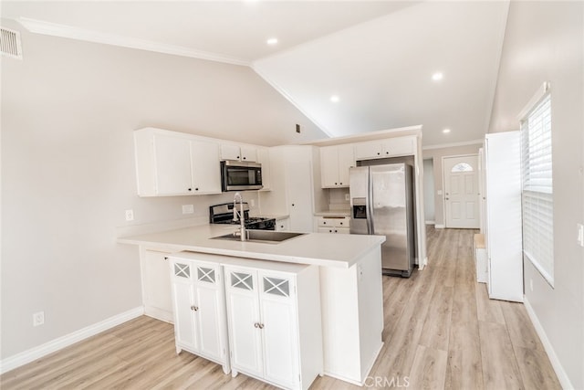 kitchen featuring stainless steel appliances, kitchen peninsula, vaulted ceiling, and white cabinets