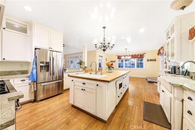 kitchen with sink, white cabinetry, a kitchen island with sink, stainless steel fridge with ice dispenser, and decorative light fixtures