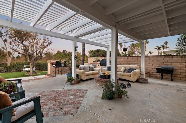 patio terrace at dusk featuring outdoor dry bar, grilling area, a pergola, fence private yard, and an outdoor living space