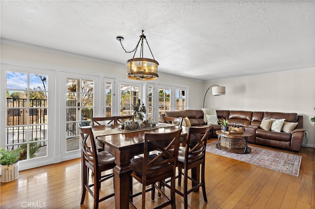 dining space featuring a textured ceiling, plenty of natural light, wood finished floors, and crown molding