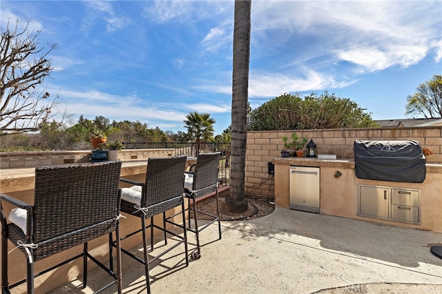 view of patio / terrace featuring a grill, fence, exterior kitchen, and outdoor wet bar