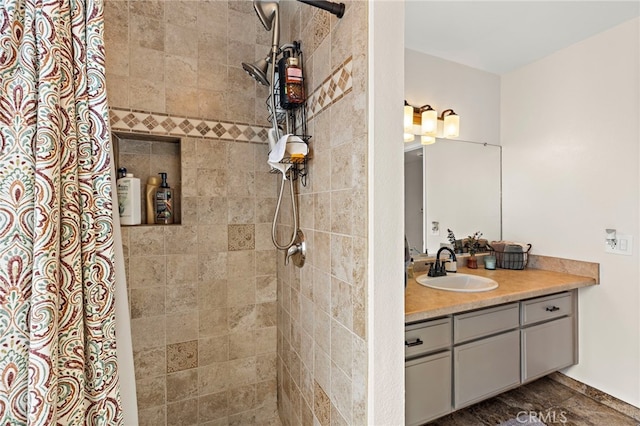 bathroom with a tile shower and vanity