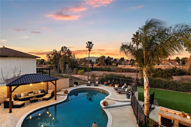 pool at dusk featuring a fenced in pool, a fenced backyard, a gazebo, a patio area, and outdoor lounge area