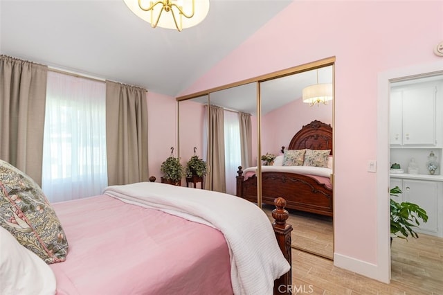 bedroom featuring an inviting chandelier, lofted ceiling, and a closet