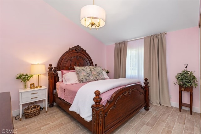 bedroom featuring an inviting chandelier, vaulted ceiling, and light hardwood / wood-style flooring