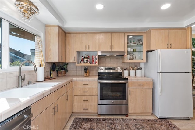 kitchen with stainless steel appliances, tile counters, and light brown cabinetry