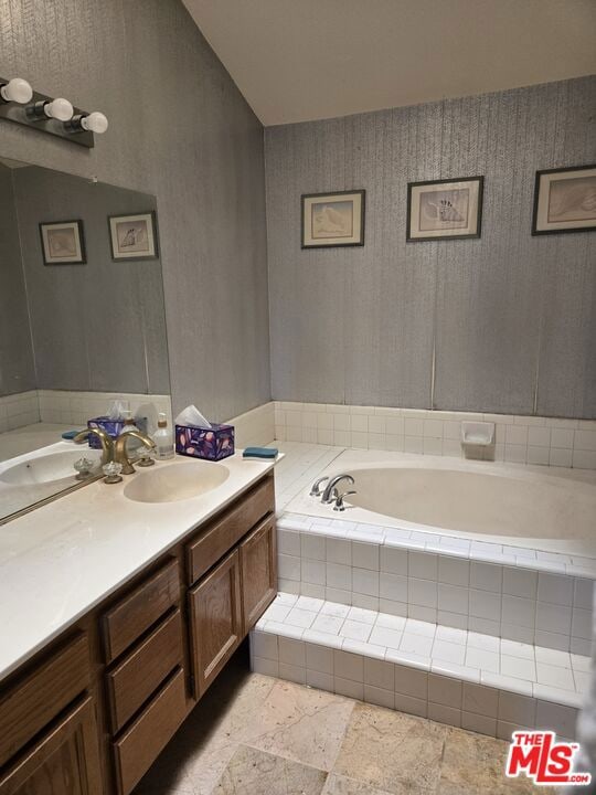 bathroom featuring vanity and a relaxing tiled tub