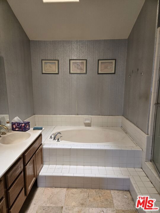 bathroom featuring vanity and a relaxing tiled tub