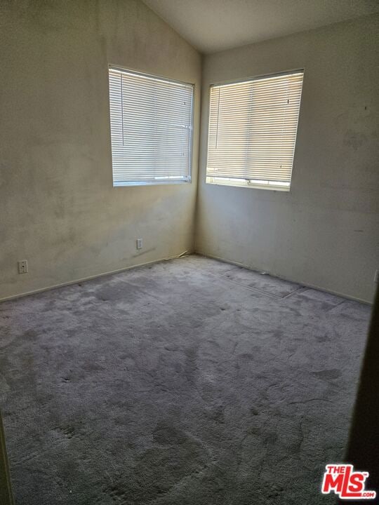 unfurnished room featuring lofted ceiling and carpet