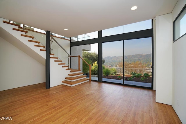 unfurnished living room with a mountain view, light hardwood / wood-style flooring, and floor to ceiling windows