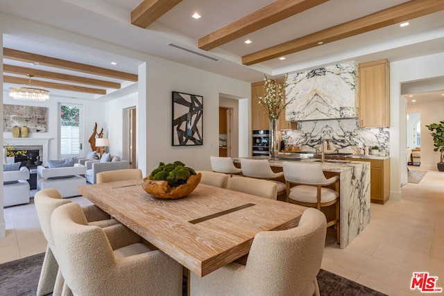 tiled dining space with beam ceiling, a chandelier, and sink