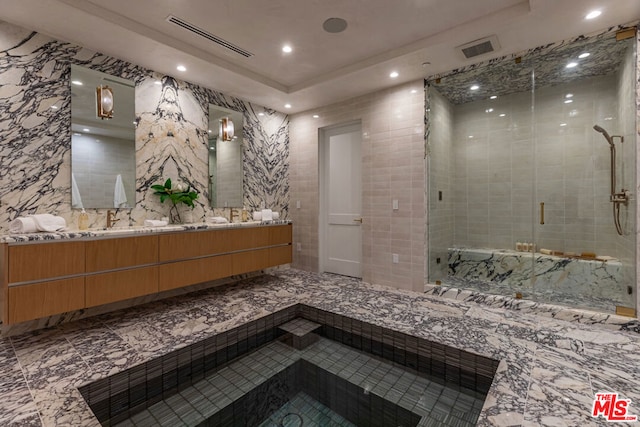 bathroom with vanity, a shower with shower door, and tile walls