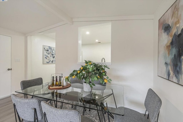 dining room with wood-type flooring and lofted ceiling with beams