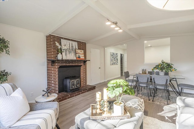 living room featuring hardwood / wood-style flooring, lofted ceiling with beams, and a wood stove