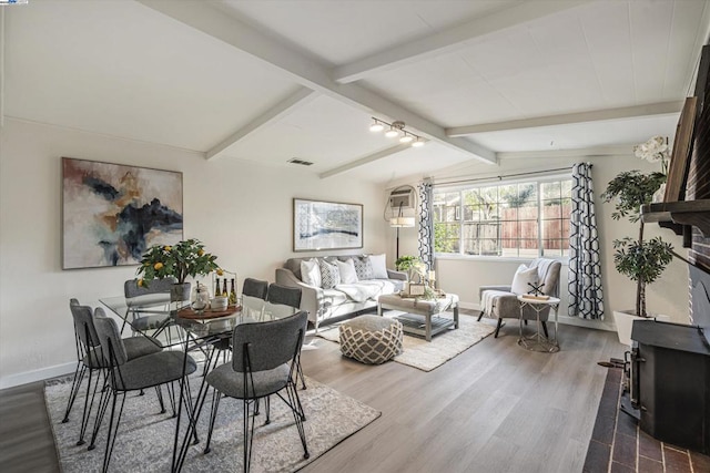 interior space with vaulted ceiling with beams, hardwood / wood-style flooring, and track lighting