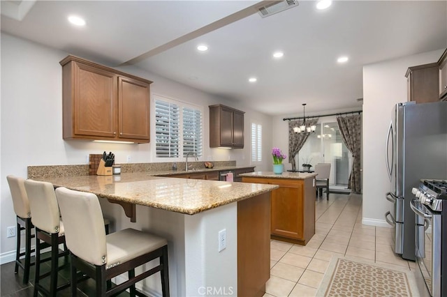 kitchen featuring a breakfast bar area, kitchen peninsula, a kitchen island, pendant lighting, and stainless steel appliances