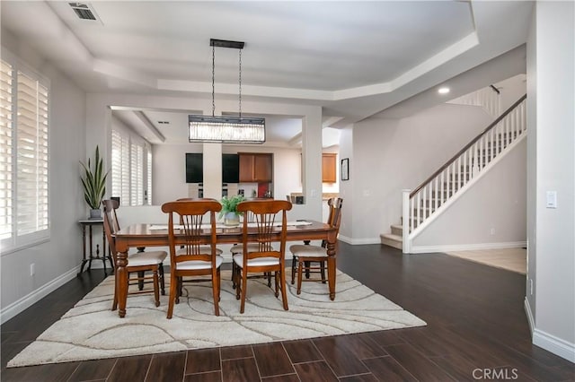 dining area with dark hardwood / wood-style flooring and a raised ceiling