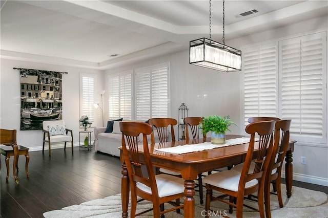 dining space with dark hardwood / wood-style floors and a tray ceiling