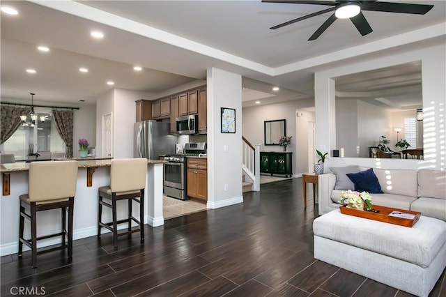 kitchen with dark wood-type flooring, a breakfast bar area, light stone counters, decorative light fixtures, and stainless steel appliances