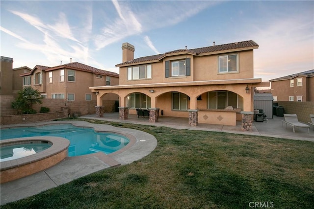 rear view of property with a pool with hot tub, a patio area, a lawn, and exterior bar