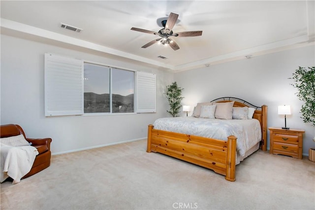 carpeted bedroom featuring ceiling fan and a tray ceiling