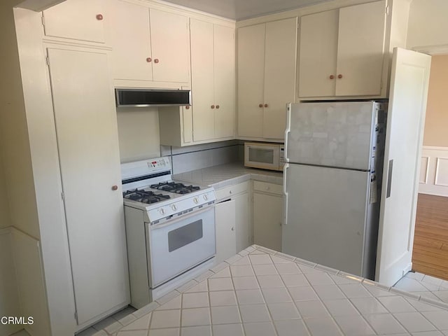 kitchen featuring white cabinetry, white appliances, tile countertops, and range hood