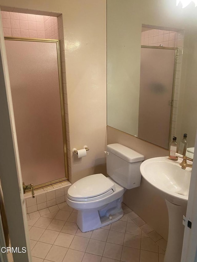 bathroom featuring a shower with door, tile patterned floors, and toilet